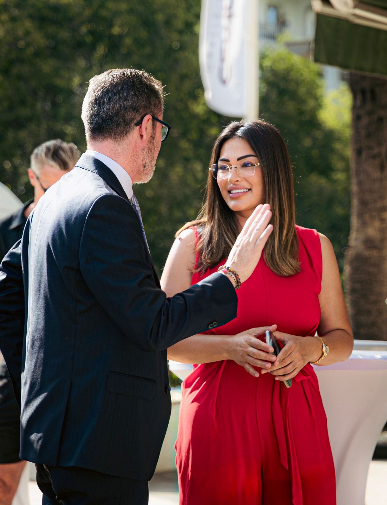 Avida advisor in a red dress in conversation with a client in a suit outdoors in Marbella